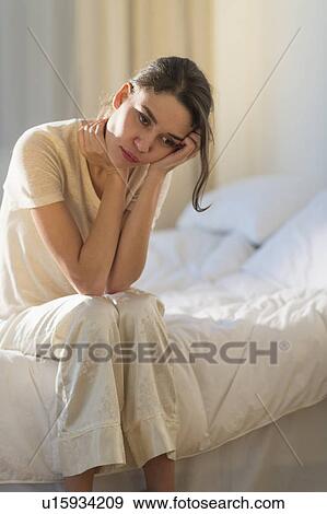 Young woman sitting on bed with headache View Large Photo Image Stock Photo - Young woman sitting on bed with headache. Fotosearch