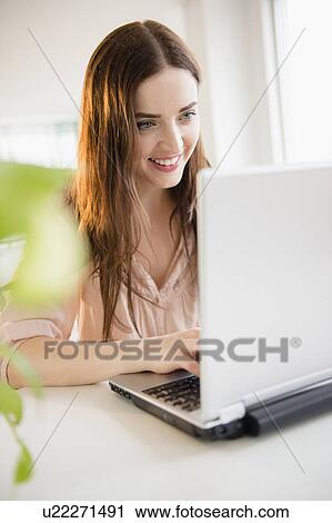 Stock Image - Young woman using laptop. Fotosearch