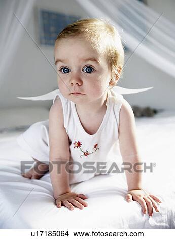 Picture - Baby girl in fairy wings crawling on bed. Fotosearch