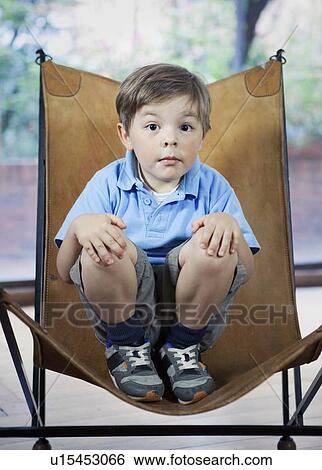 Boy crouching in camp chair View Large Photo Image Stock Photograph - Boy crouching in camp chair. Fotosearch