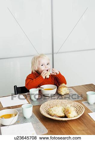 Stock Photo - Boy eating lunch at table. Fotosearch