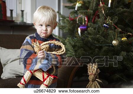 Boy holding toy by Christmas tree View Large Photo Image Stock Photo - Boy holding toy by Christmas tree. Fotosearch