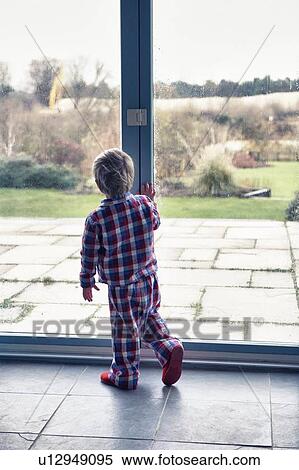 Boy in pajamas looking out window View Large Photo Image Stock Photography - Boy in pajamas looking out window. Fotosearch