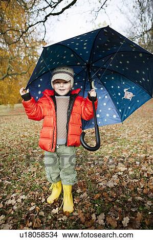 Picture - Boy in rain boots and umbrella in park. Fotosearch