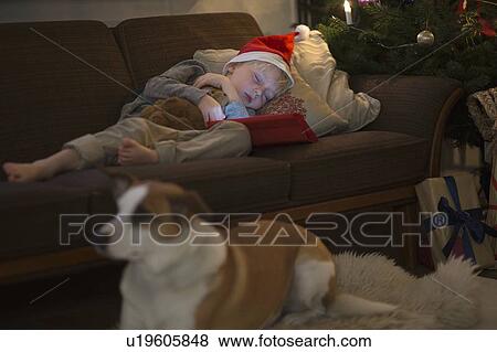Stock Photo - Boy in Santa hat sleeping on sofa. Fotosearch
