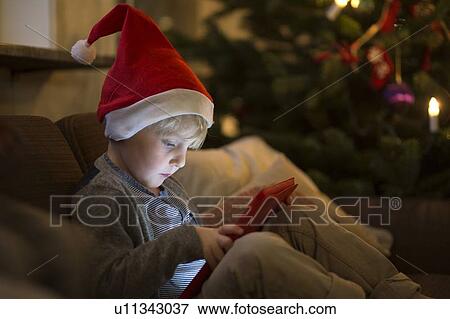 Boy in Santa hat using tablet computer View Large Photo Image Stock Photo - Boy in Santa hat using tablet computer. Fotosearch