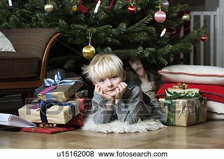 Boy laying under Christmas tree View Large Photo Image Stock Photo - Boy laying under Christmas tree. Fotosearch