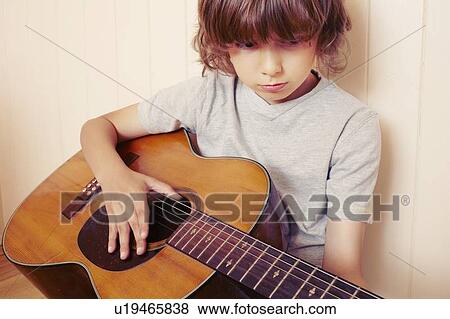 Boy playing guitar indoors View Large Photo Image Stock Photo - Boy playing guitar indoors. Fotosearch