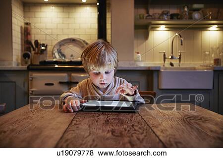 Boy using tablet computer at table View Large Photo Image Stock Photo - Boy using tablet computer at table. Fotosearch
