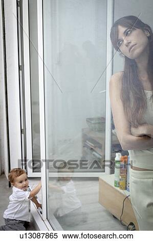Boy watching mother look out window View Large Photo Image Stock Photography - Boy watching mother look out window. Fotosearch