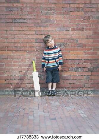 Boy with cricket bat against brick wall View Large Photo Image Stock Image - Boy with cricket bat against brick wall. Fotosearch