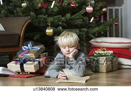 Boy writing under Christmas tree View Large Photo Image Stock Photo - Boy writing under Christmas tree. Fotosearch