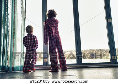 Stock Image - Boys in pajamas looking out window. Fotosearch
