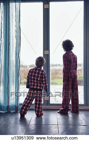 Stock Photo - Boys in pajamas looking out window. Fotosearch