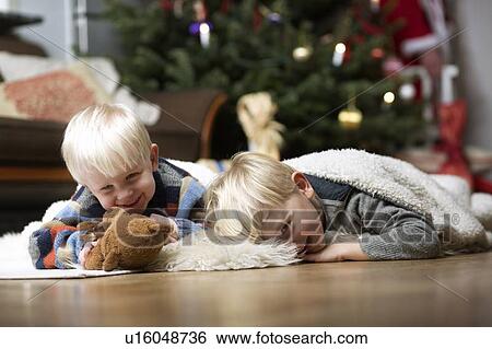 Stock Photograph - Boys playing on floor by Christmas tree. Fotosearch
