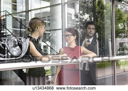 Stock Photo - Business people talking by window. Fotosearch