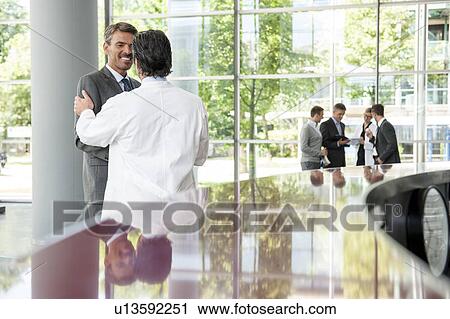 Stock Image - Businessman and doctor shaking hands. Fotosearch
