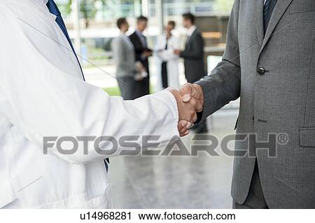 Stock Image - Businessman and doctor shaking hands. Fotosearch