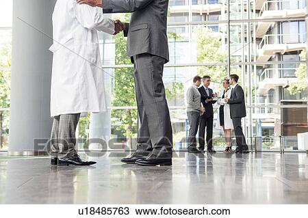 Stock Image - Businessman and doctor shaking hands. Fotosearch
