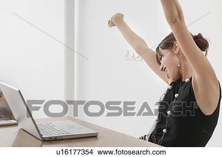 Businesswoman cheering at desk View Large Photo Image Picture - Businesswoman cheering at desk. Fotosearch