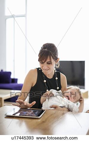 Stock Image - Businesswoman holding crying son. Fotosearch
