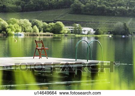 Chair on wooden pier in still rural lake View Large Photo Image Picture - Chair on wooden pier in still rural lake. Fotosearch