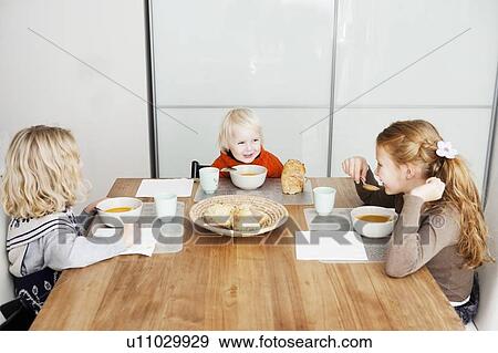 Children eating lunch at table View Large Photo Image Stock Photo - Children eating lunch at table. Fotosearch