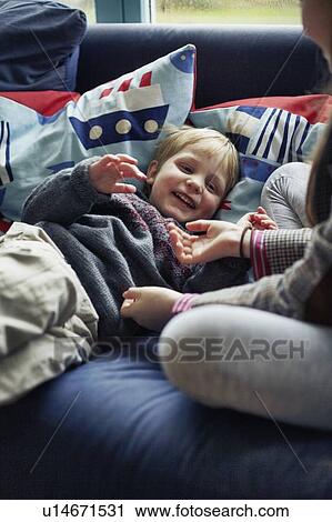 Stock Image - Children playing together on sofa. Fotosearch