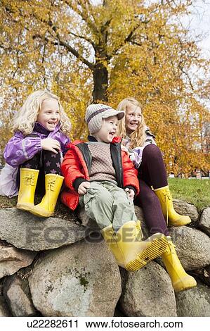 Stock Image - Children wearing rain boots outdoors. Fotosearch