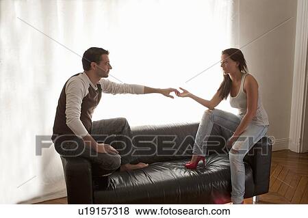 Stock Photo - Couple holding hands on leather sofa. Fotosearch