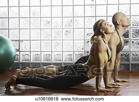 Stock Photo - Couple practicing yoga together in gym. Fotosearch