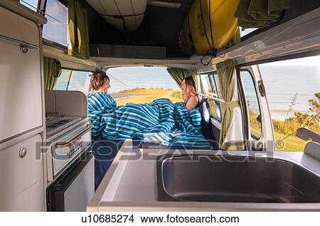 Picture - Couple under comforter in trailer. Fotosearch