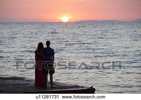 Couple watching sunset on pier View Large Photo Image Stock Image - Couple watching sunset on pier. Fotosearch