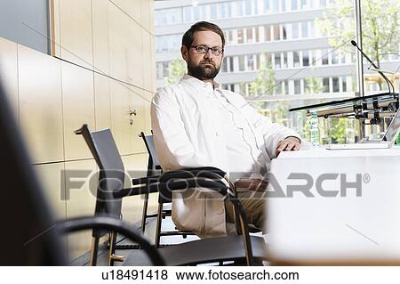 Stock Photo - Doctor at desk in conference room. Fotosearch
