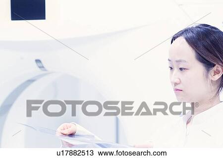 Stock Image - Doctor operating CT scanner in hospital. Fotosearch
