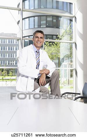 Doctor sitting on desk in meeting room View Large Photo Image Stock Image - Doctor sitting on desk in meeting room. Fotosearch
