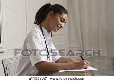 Stock Image - Doctor taking notes in office. Fotosearch