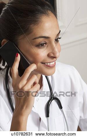 Doctor talking on cell phone in office View Large Photo Image Stock Image - Doctor talking on cell phone in office. Fotosearch