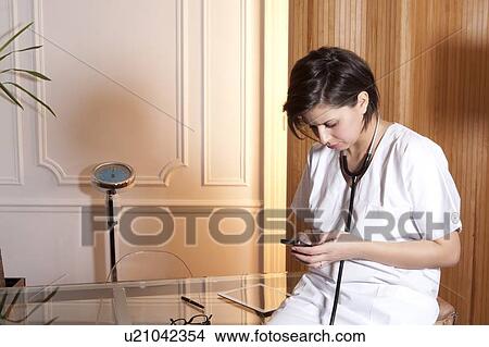 Doctor using cell phone in office View Large Photo Image Picture - Doctor using cell phone in office. Fotosearch