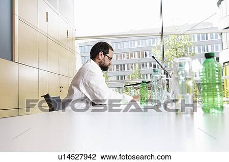 Stock Image - Doctor using laptop at desk. Fotosearch