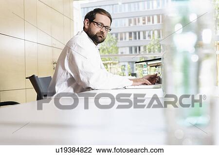 Doctor using laptop at desk View Large Photo Image Stock Image - Doctor using laptop at desk. Fotosearch