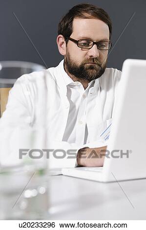 Stock Photograph - Doctor using laptop at desk. Fotosearch