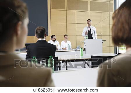 Stock Image - Doctors giving talk in conference room. Fotosearch