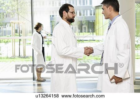Doctors shaking hands in hallway View Large Photo Image Stock Photo - Doctors shaking hands in hallway. Fotosearch