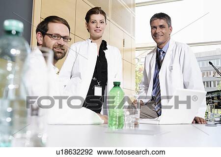 Doctors smiling at desk View Large Photo Image Stock Image - Doctors smiling at desk. Fotosearch