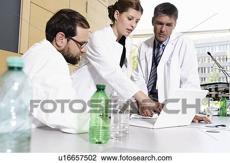 Stock Image - Doctors using laptop at desk. Fotosearch