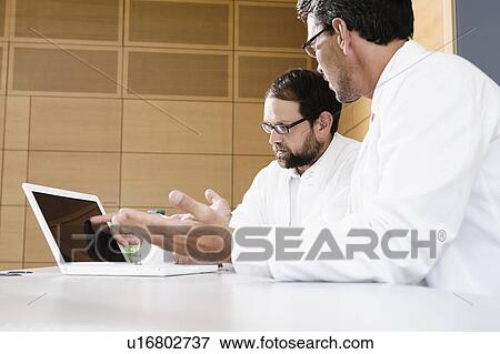 Stock Photo - Doctors using laptop at desk. Fotosearch