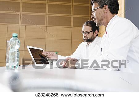 Stock Photograph - Doctors using laptop at desk. Fotosearch