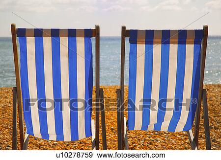 Stock Photo - Empty lawn chairs on rocky beach. Fotosearch
