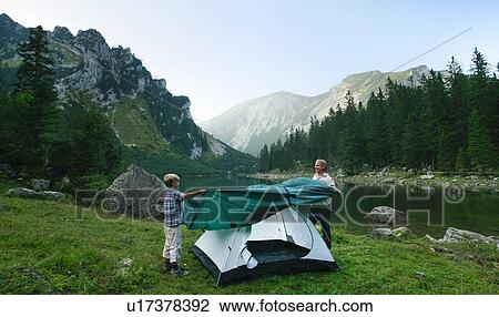 Stock Image - Father and son pitching tent together. Fotosearch